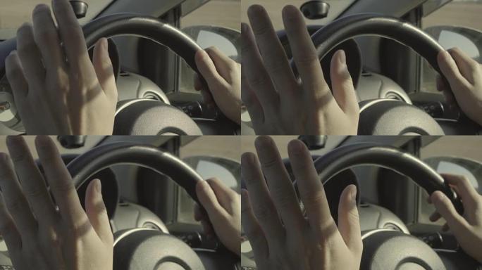 无法识别的男子驾驶汽车，将手放在方向盘上。晴天