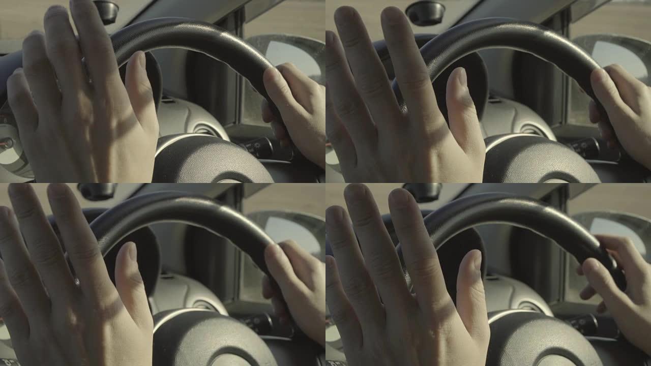 无法识别的男子驾驶汽车，将手放在方向盘上。晴天