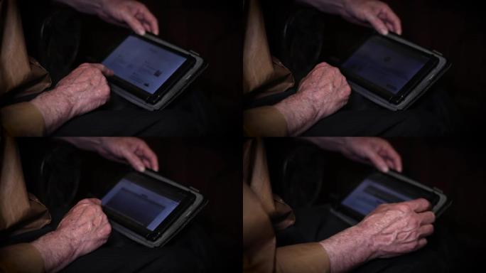 老年人使用平板电脑的手。