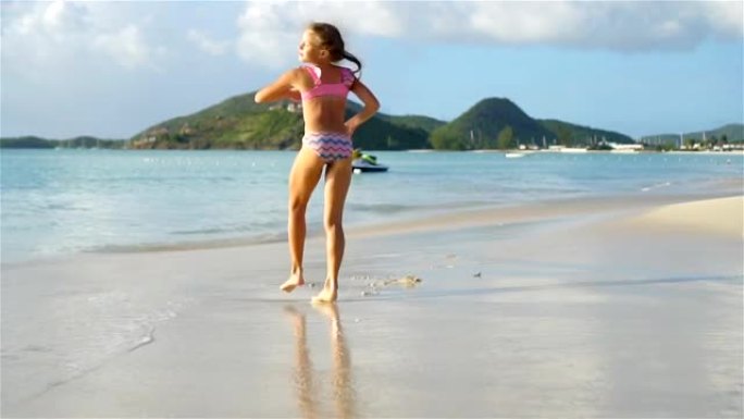 活跃的小女孩在白色海滩上做侧翻