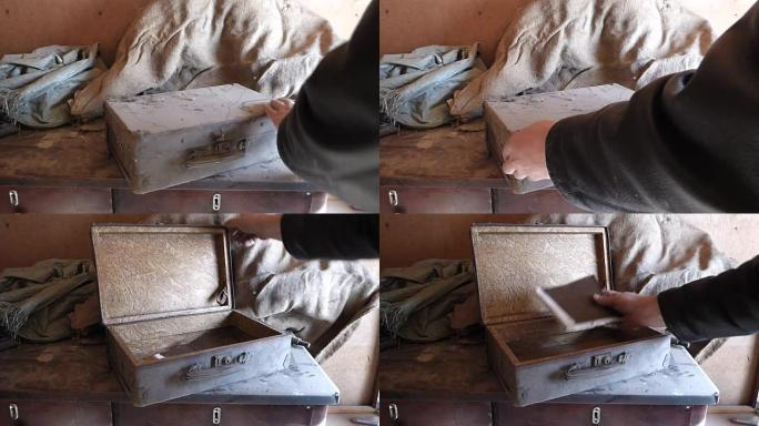高加索人把尘土飞扬的旧箱子放在木桌上，然后打开