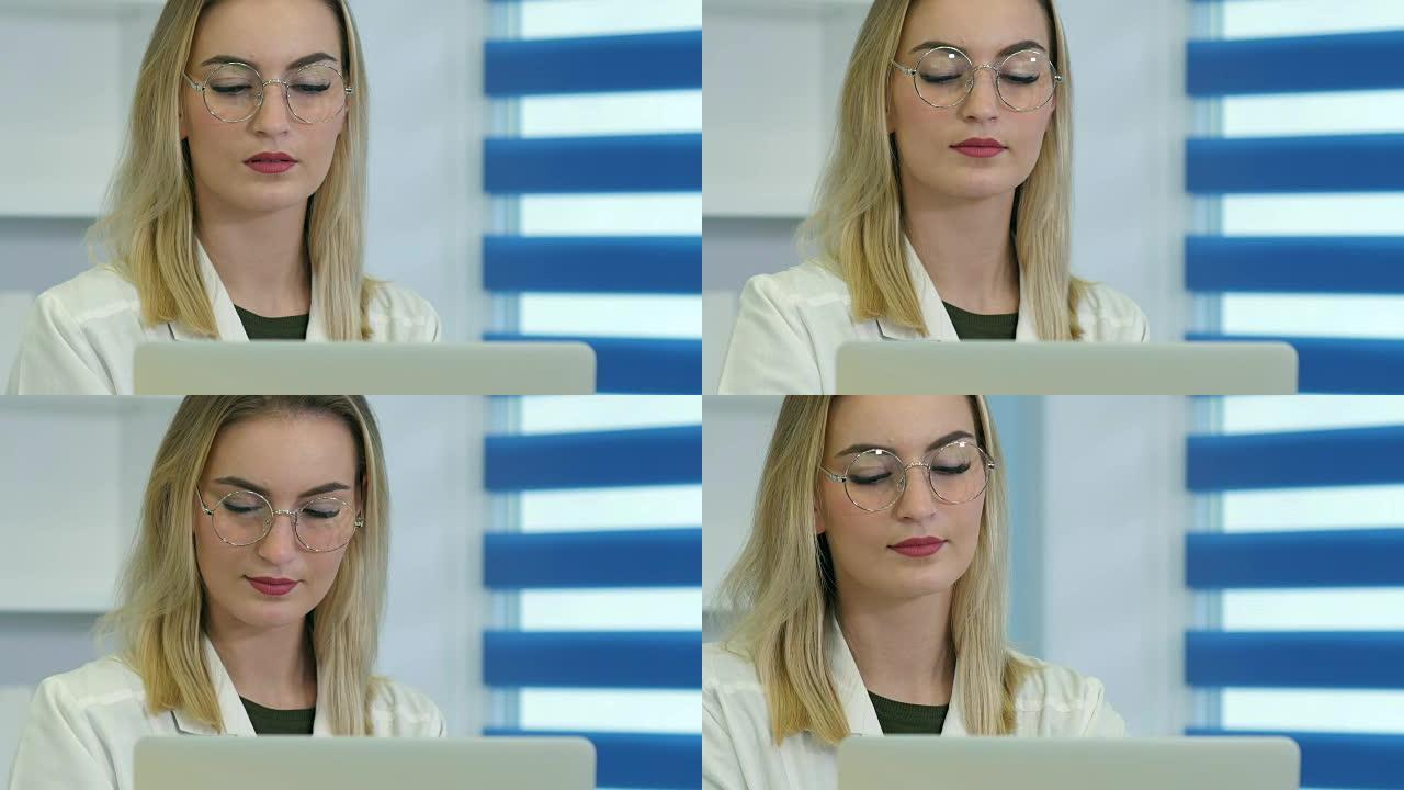 戴眼镜的女医生在前台用笔记本电脑工作