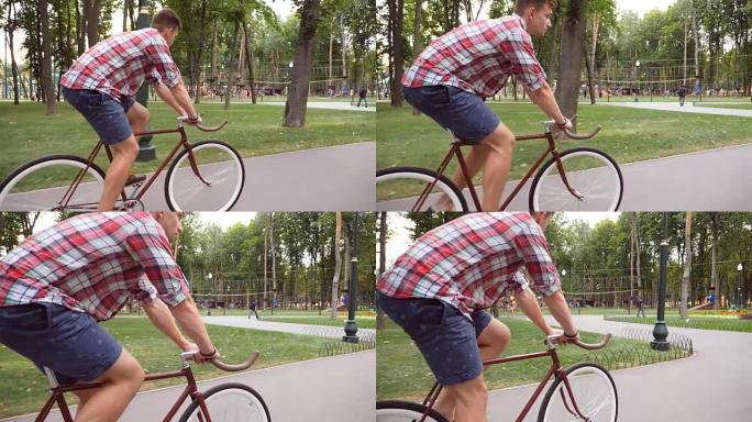 跟随年轻英俊的男人在户外骑老式自行车。运动男在公园骑自行车。健康积极的生活方式。侧视图特写