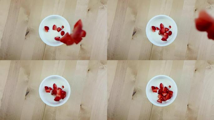 健康草莓在木桌上慢动作落在白酸奶上，健康食品的概念