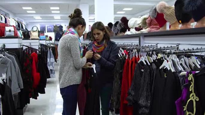 两个年轻漂亮的女孩在时尚的精品店挑选衣服。女孩们仔细看衣服，检查一下。