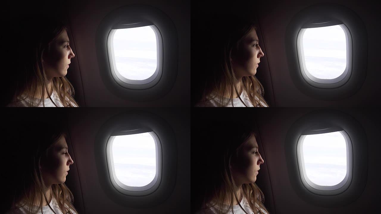 坐在飞机窗户边向外看的女孩