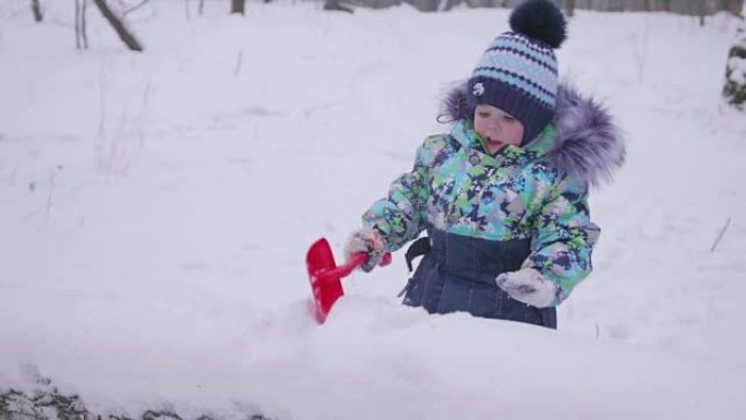 一个在冬季公园玩雪的小孩。阳光明媚的冬日。新鲜空气中的乐趣和游戏。