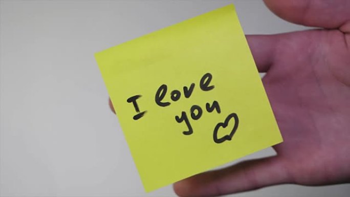 在黄纸上画 “我爱你”。白底贴纸上的题字我爱你