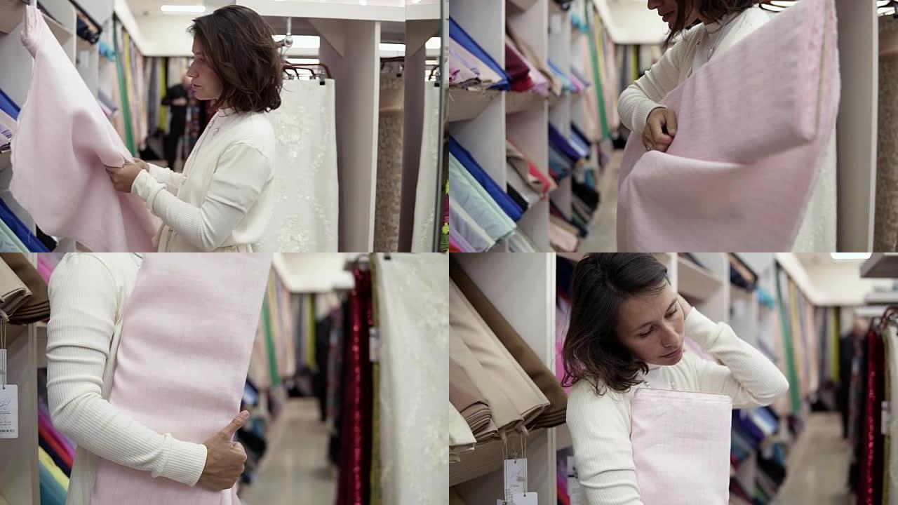 一个美丽的黑发女人在纸巾店选择一种布料。取一卷浅粉色织物，适用于身体。试穿。慢动作