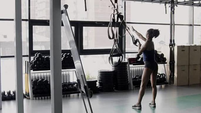 Female athlete is squatting using trx loops in spo