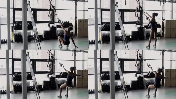 Female athlete is squatting using trx loops in spo