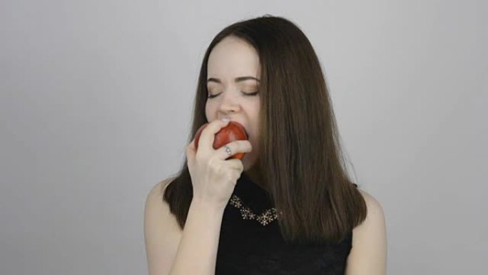 迷人的年轻女子吃了一个红苹果，微笑着