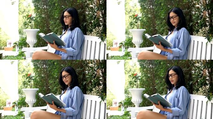 迷人的亚洲女性在花园里微笑着读书。