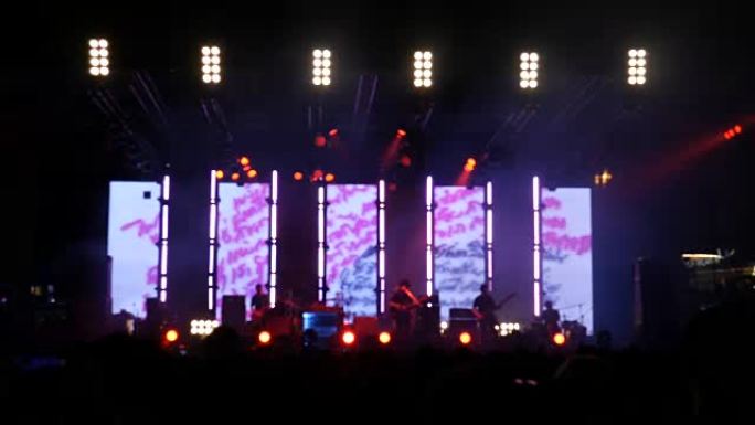 音乐会上的人群和摇滚音乐会上跳舞的人们的舞台灯光模糊。