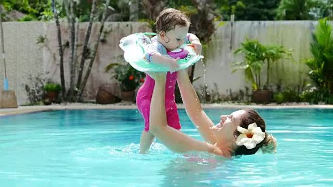 夏天在游泳池里和妈妈一起充气漂浮的女婴