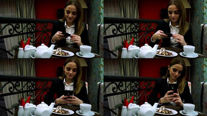 咖啡馆里一个穿着夹克和衬衫的年轻女孩拍了一张甜点和自拍的照片