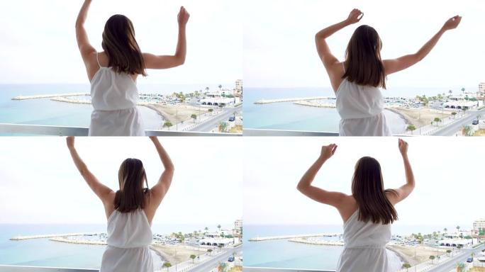 女人在海景露台上快乐地跳跃。傻女举起手臂慢动作跳舞