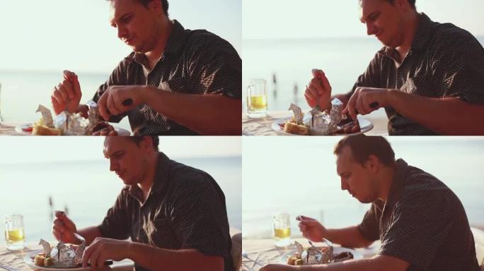 日落时，男人在沙滩咖啡馆吃烧烤肉牛排，喝啤酒。1920x1080