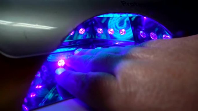 指甲用紫外线灯的手。水疗护理。指甲处理，用紫外线灯干燥漆