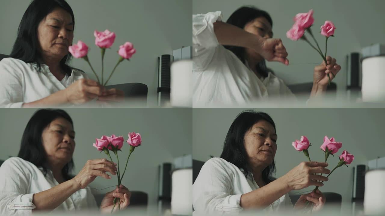 泰国高级妇女正在制作纸粉红玫瑰工艺品作为礼物