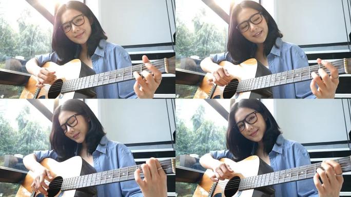 迷人的亚洲女人在家里微笑着弹吉他。