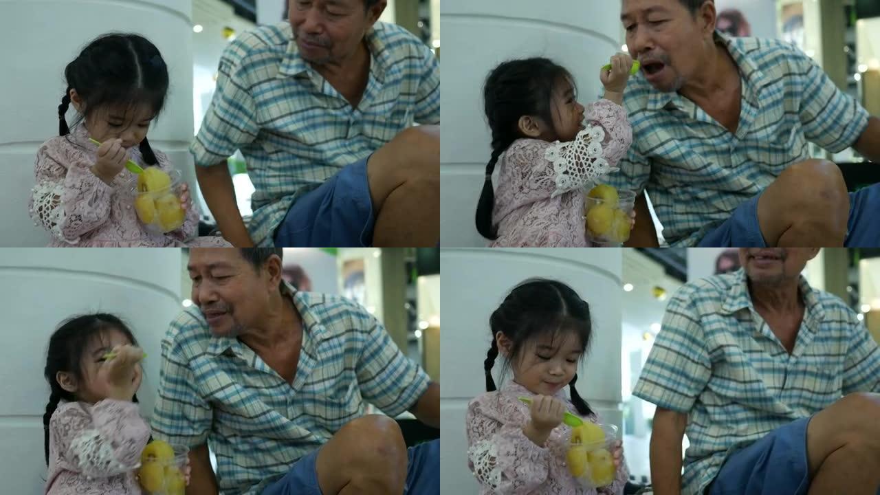 可爱的小女孩和爷爷一起吃水果