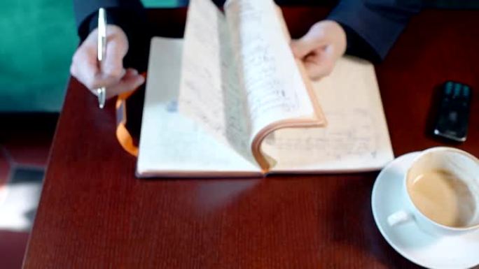 年轻的商人正在使用笔记本电脑，坐在咖啡馆内部的桌子旁