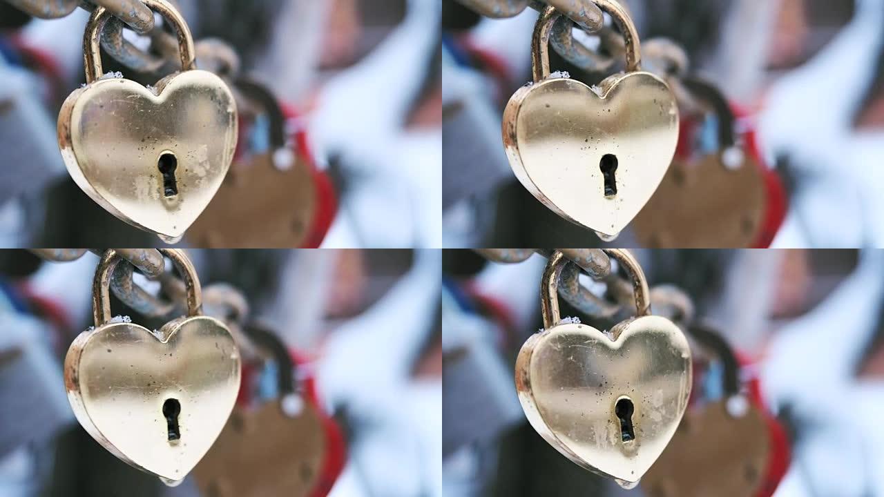 金属金锁在冬天在户外风中摆动的链条上的心形。爱情和忠诚婚礼习俗的象征