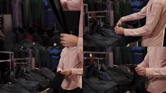 年轻人正在服装店检查牛仔长裤的价格，触摸商品