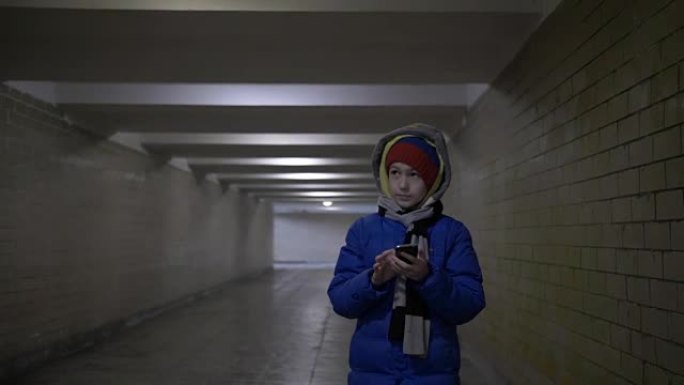 男孩在冬天用电话走隧道
