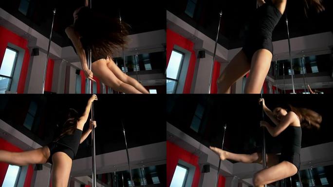 在工作室里，年轻性感的女人在杆子上旋转表演钢管舞