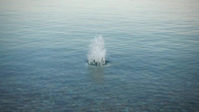 石头慢慢掉进水里。慢动作。