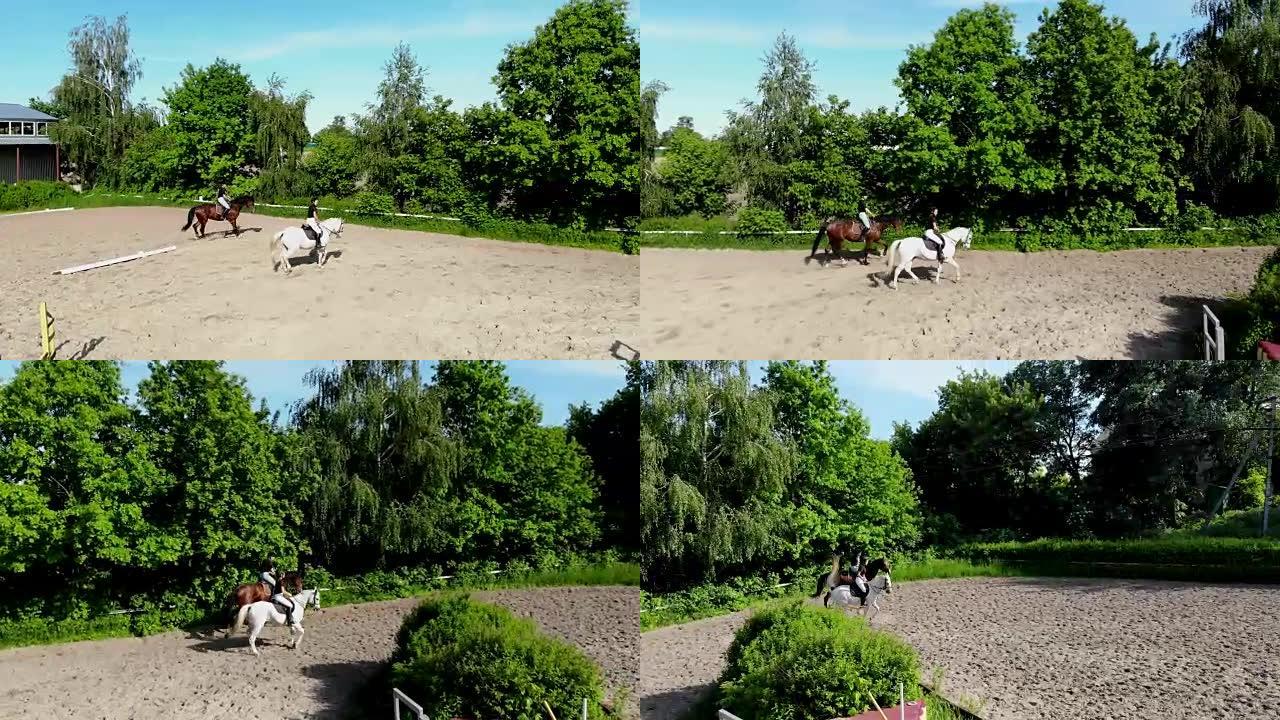 从上方观看，空中视频拍摄，训练沙场，游乐场，骑手，骑师骑马，与马一起进行各种练习，在障碍物旁边。夏天