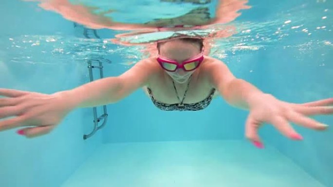一位戴着眼镜游泳的年轻女子在水下游泳