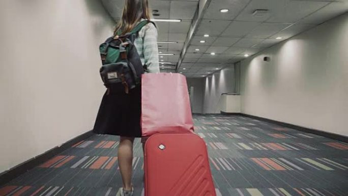 带着红色行李的女性旅行者走过机场航站楼