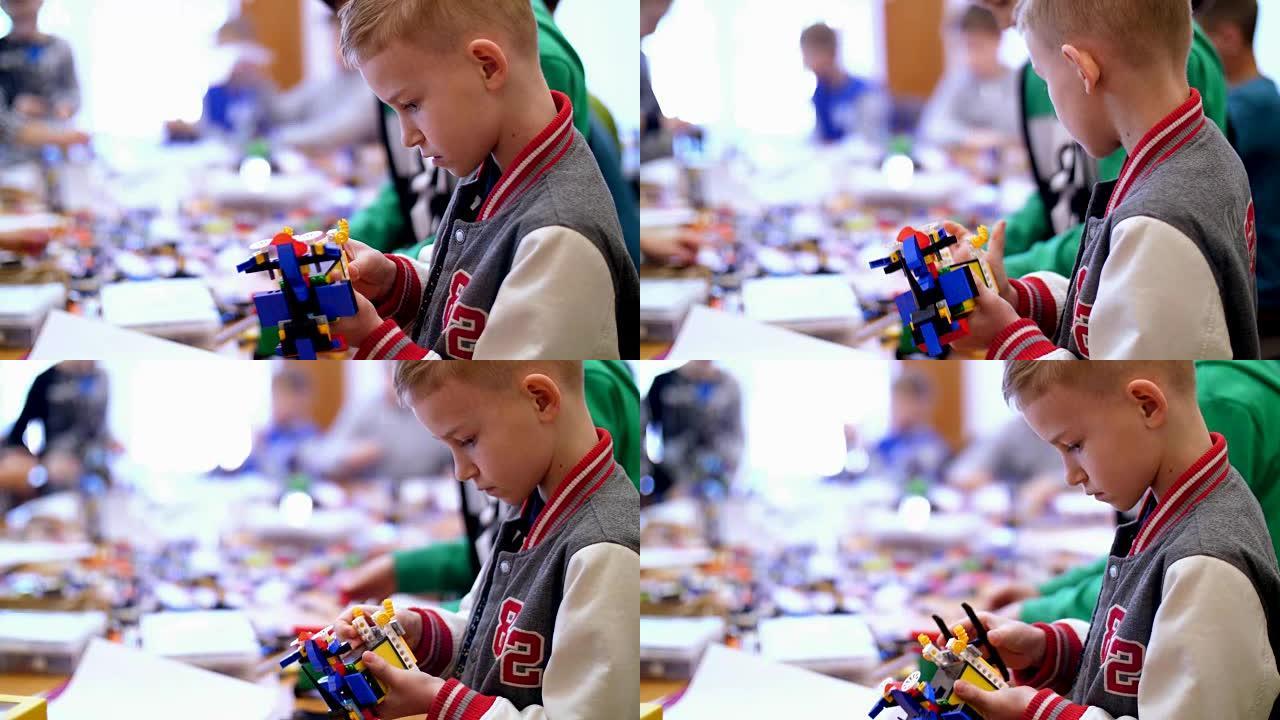 10岁的男孩，从立方体，盘子，电路，电线在设计师中扮演角色。一个小发明家从设计师的不同部分创建机器人