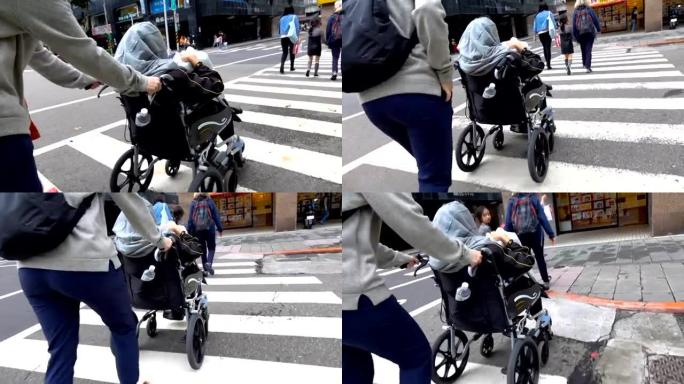 年轻女子推着轮椅过马路