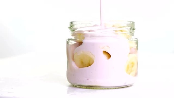 白色背景的罐子里有香蕉的新鲜水果酸奶。全高清