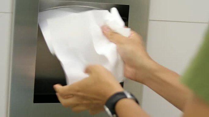 男人在用液体肥皂洗手后用纸巾擦手。