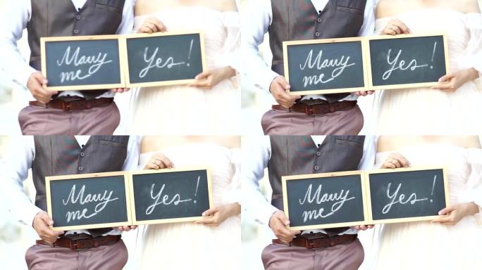 婚礼概念。你愿意嫁给我吗？是的，在新婚夫妇展示的黑板上手写的。