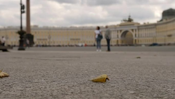慢动作: 阴天里，黄叶在总参谋部背景的宫殿广场上飞舞-俄罗斯圣彼得堡