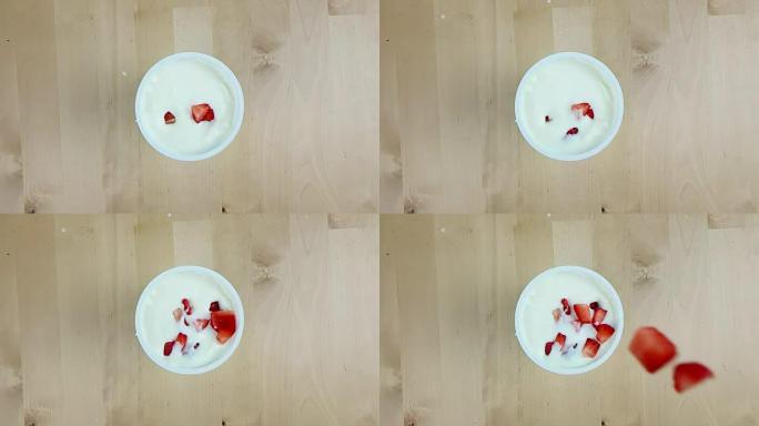 健康草莓在木桌上慢动作落在白酸奶上，健康食品的概念