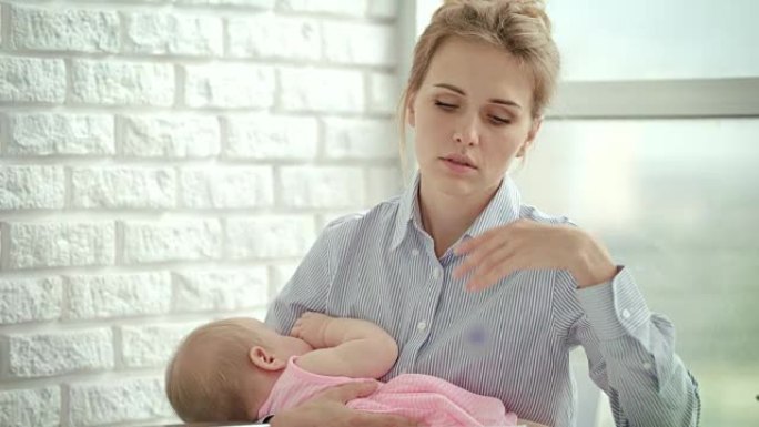 不快乐的女人手里拿着熟睡的婴儿。压力母亲概念