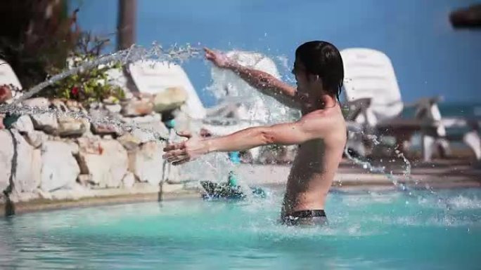 戴着墨镜的年轻英俊男子在旅行假期的晴天在游泳池的水流下放松。1920x1080