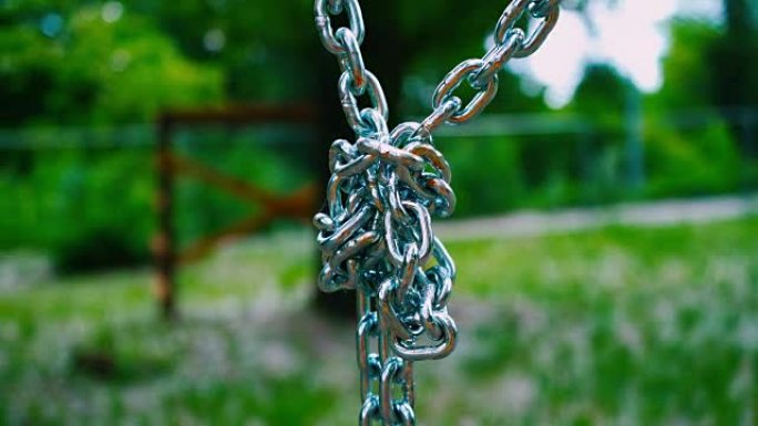 向下悬挂的坚固的钢链连接成一个结。夏季公园中儿童景点的金属坐骑
