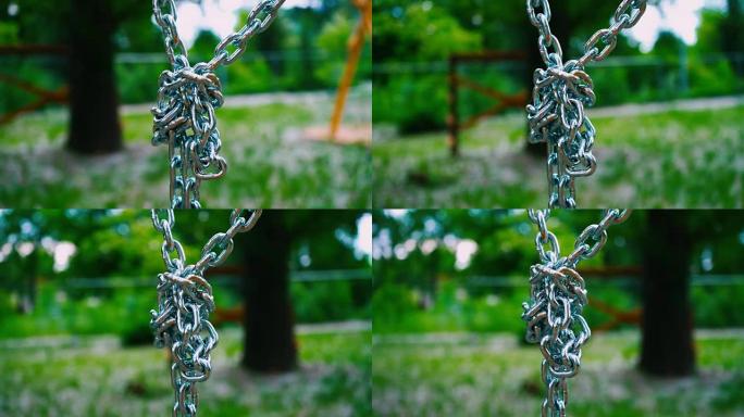 向下悬挂的坚固的钢链连接成一个结。夏季公园中儿童景点的金属坐骑