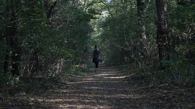 在炎热的夏日，迷人的年轻女子在大自然中慢跑穿过阴凉的森林，以改善她的精神卫生