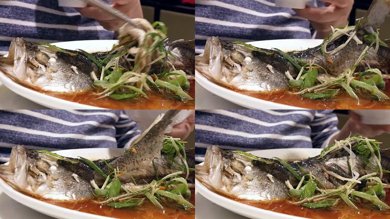 女人在餐厅吃香草和蔬菜蒸鲈鱼的动作