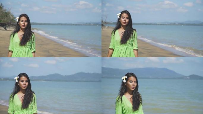 美丽的亚洲女孩走在海滩上，穿着绿色的裙子。