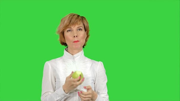 年轻女子在绿色屏幕上吃青苹果的肖像，色键